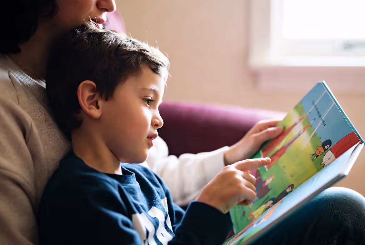 Parent and kindergarten child practicing shared reading with picture book